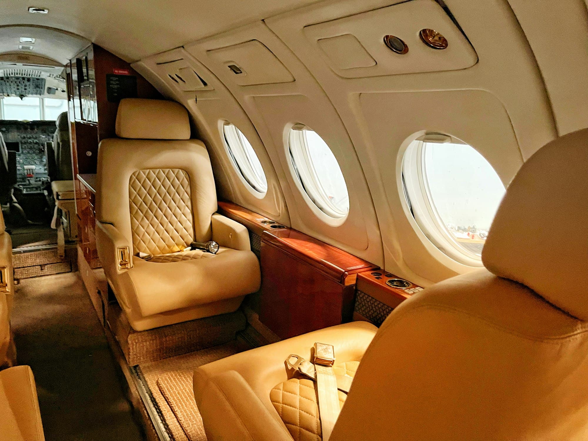 Private jet cabin with cream leather seats and warm sunlight through oval windows