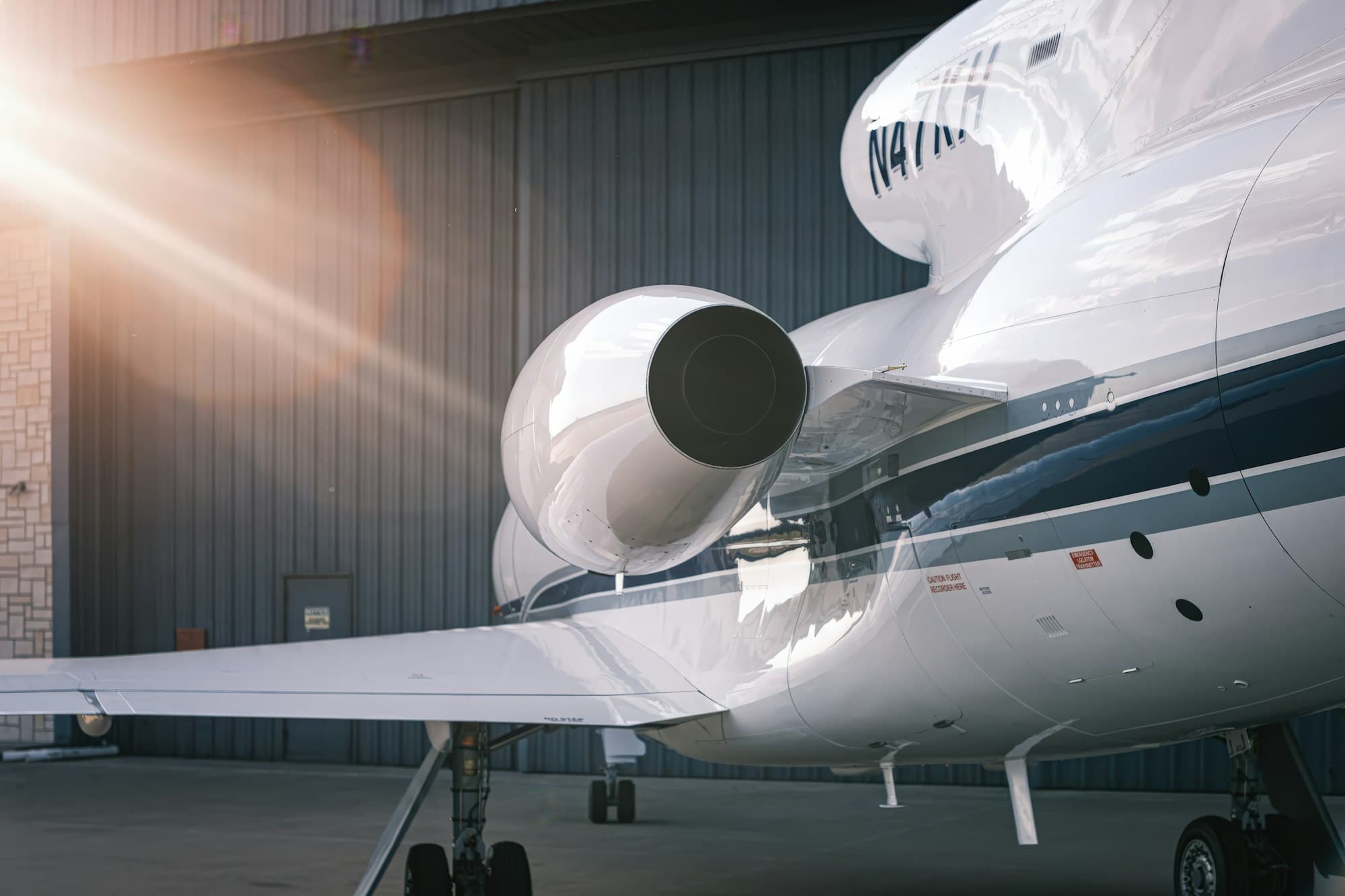 Rear engine nacelle and polished fuselage of a business jet beside a hangar